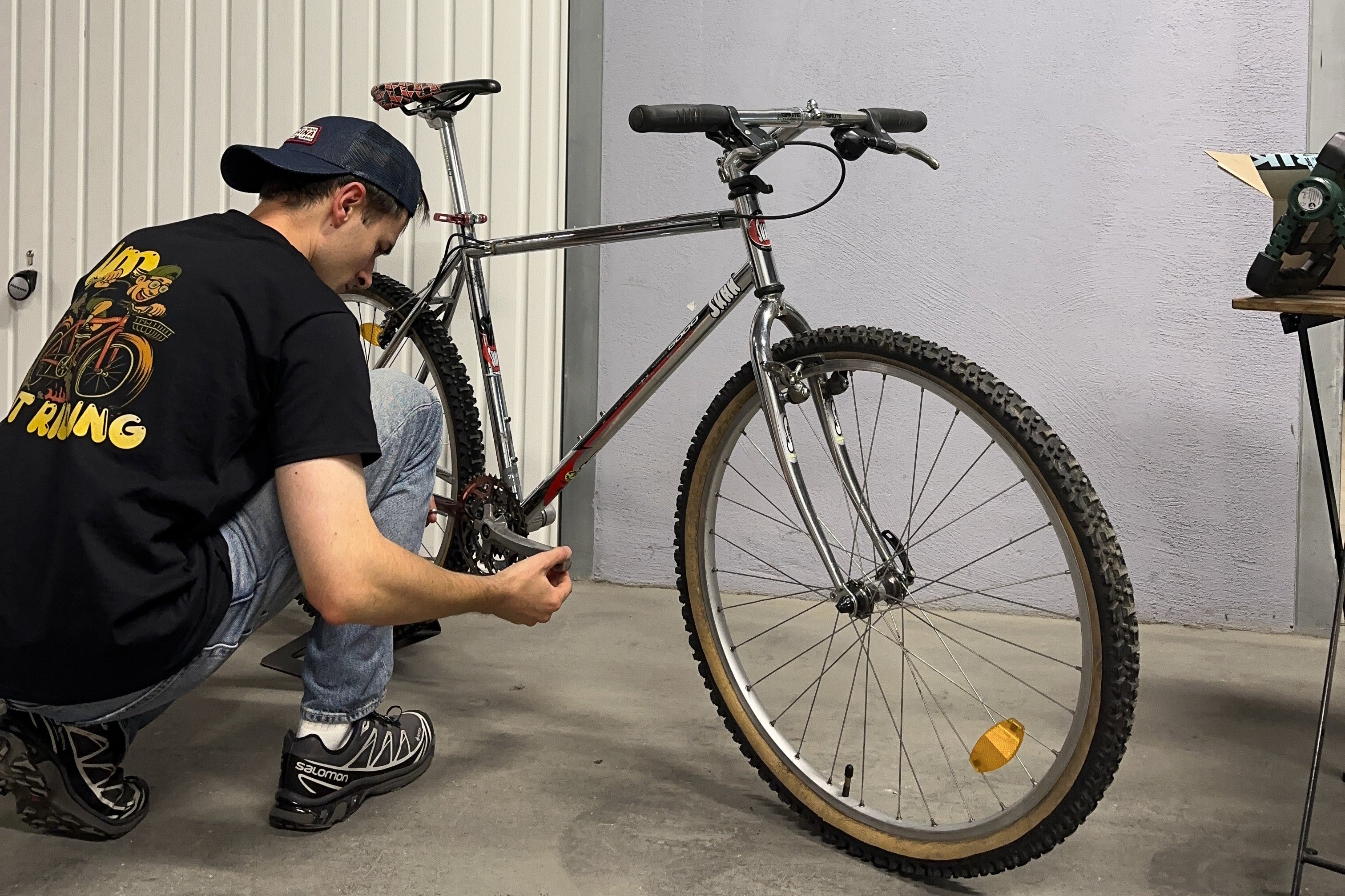 Person fixing a bicycle tire in a garage.